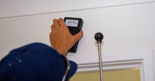 Technician using a moisture meter to inspect a wall