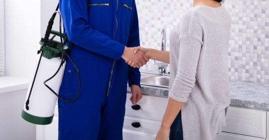 Pest Control Technician Shaking Hands With Homeowner