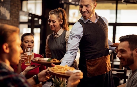 Server at a restaurant passing food to a customer